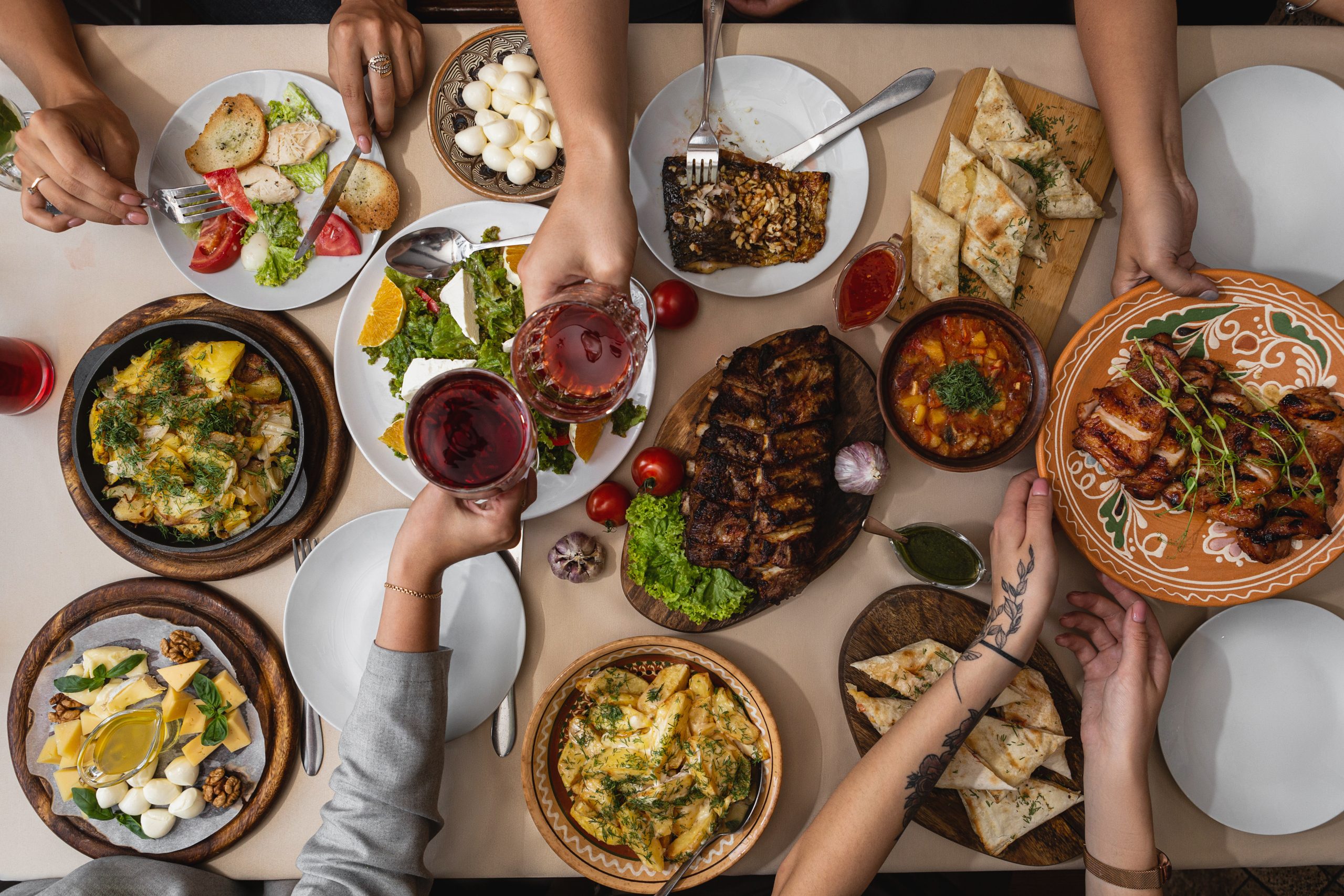 wide and tasty table covered with delicious Ukrainian cuisine on which sits a large family or friends their hands at the table during meals Italienische Antipasti mit einem Glas Rotwein