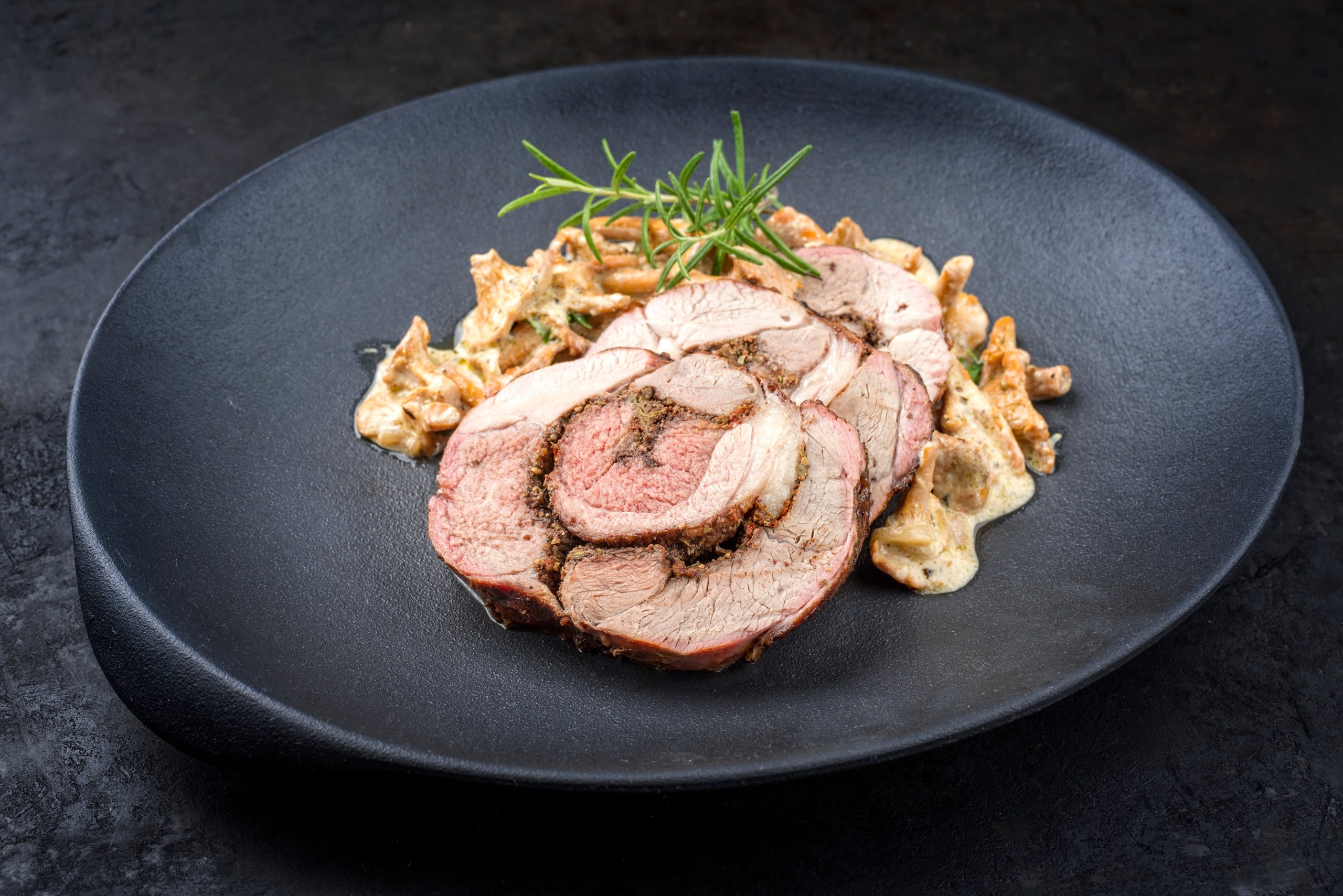 Traditioneller französischer geschmorter Lammbraten aufgeschnitten mit Pfifferlingen in Rahmsauce angeboten als close-up auf einem Design Teller