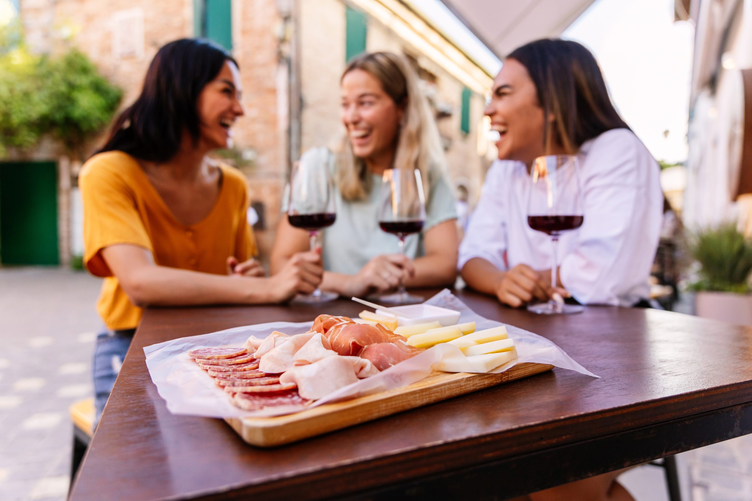 Three happy diverse women having fun together enjoying red wine at restaurant Drei glückliche Frauen sind Gäste in einem spanischen Restaurant