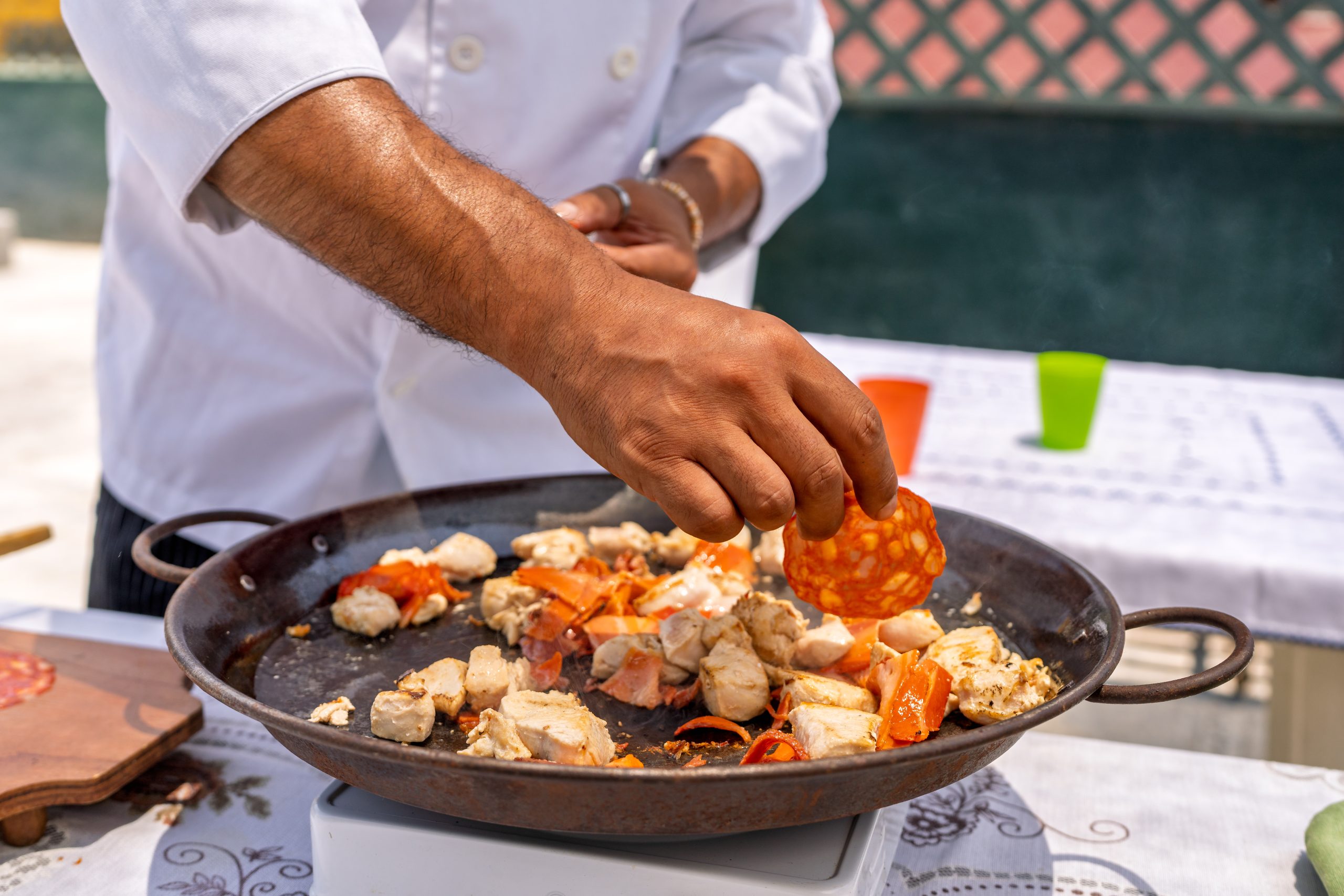 Chef adding chorizo to paella with chicken and vegetables Spanisches Restaurant mit traditioneller Küche wie Paella